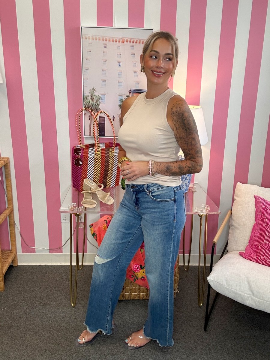 Woman standing in a room with pink and white striped wallpaper, holding a phone.