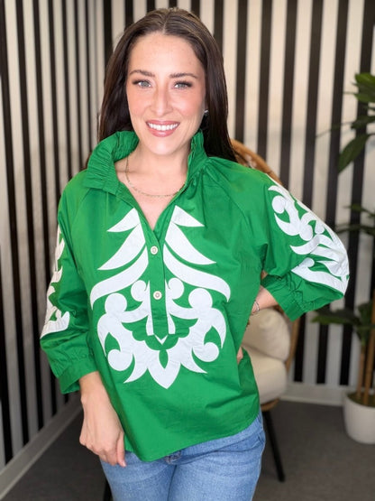 Woman wearing a green jacket with white patterns indoors