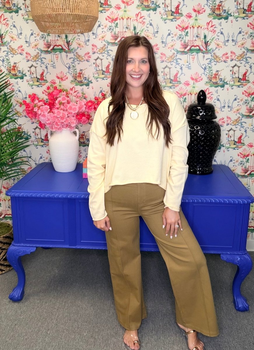 Woman standing in front of a colorful floral-patterned wall with a blue table and decorative items.