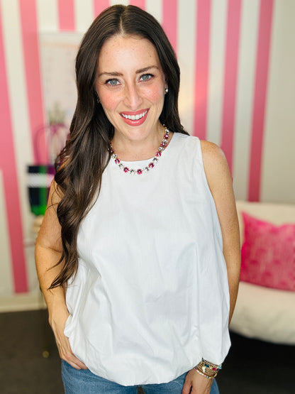 Woman wearing a white sleeveless top with a pink and white striped background