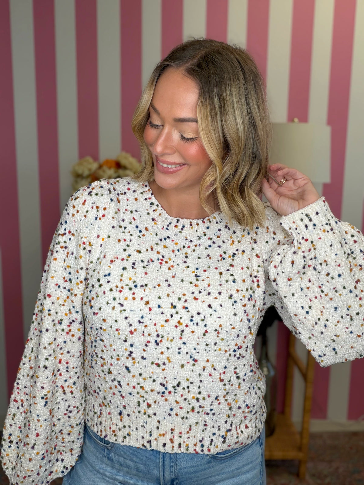 woman standing in a white sweater with polka dots