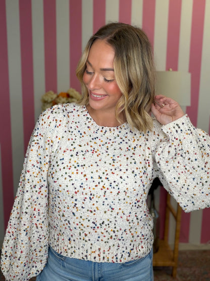 woman standing in a white sweater with polka dots