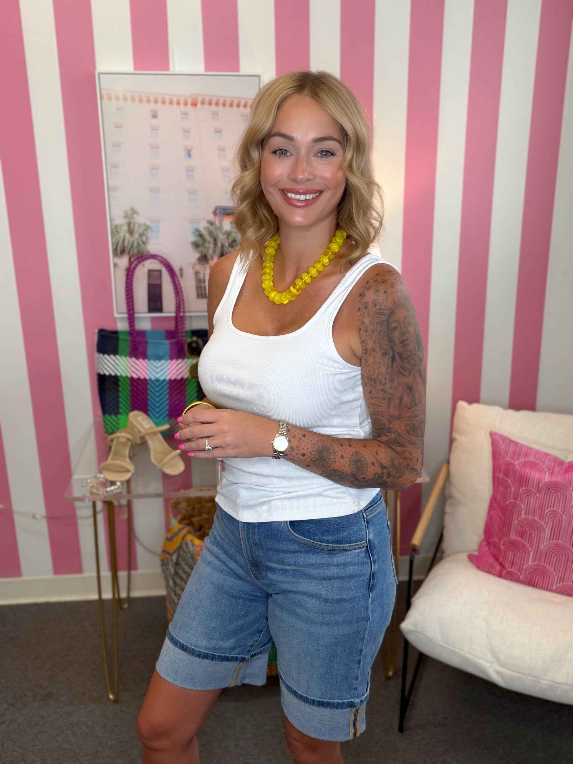 Woman standing in a room with pink and white striped walls, holding a colorful bag.