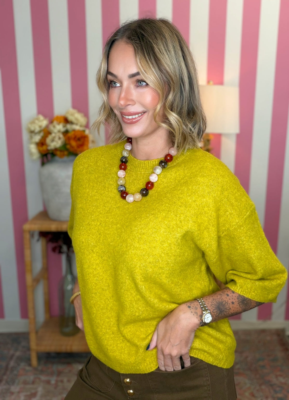 woman standing in green yellow short sleeve sweater.