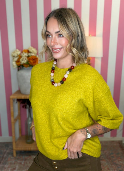 woman standing in green yellow short sleeve sweater.
