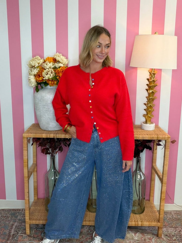 woman standing sparkly barrel jeans and a red sweater