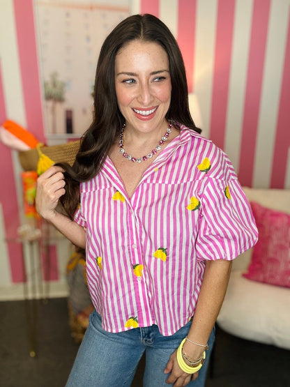 Woman wearing a pink and white striped shirt with yellow accents in a room with pink and white striped walls.