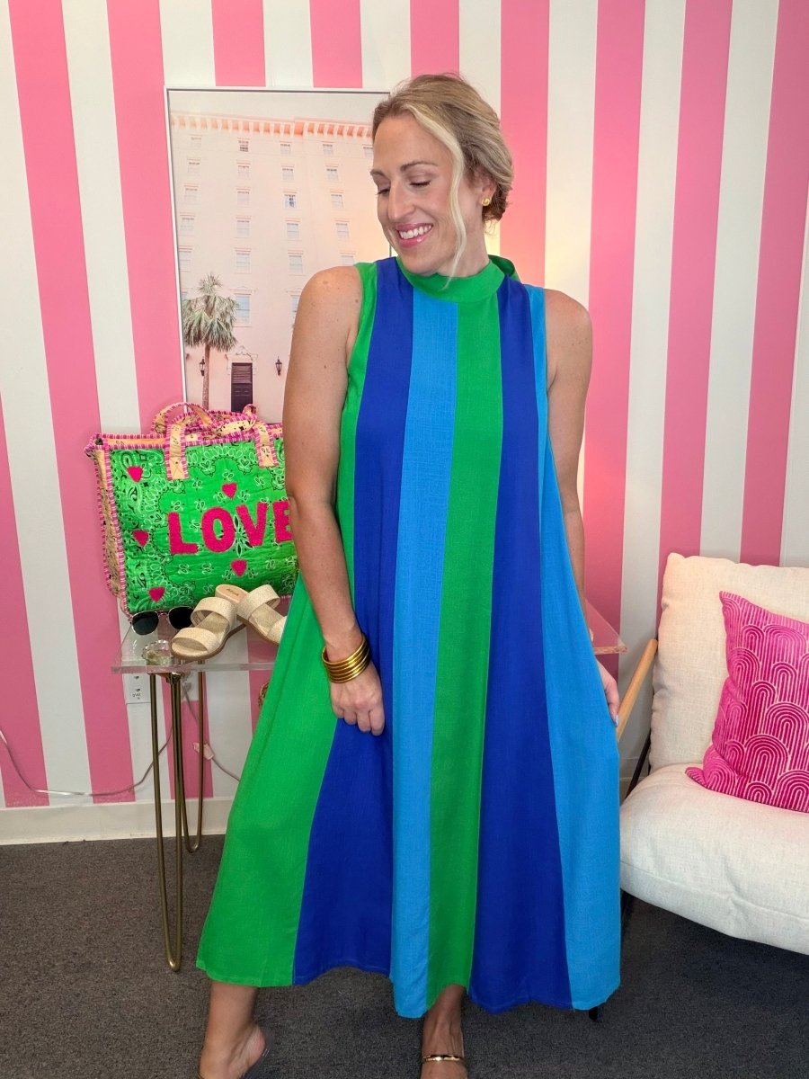 Woman wearing a blue and green striped dress in a room with pink and white striped walls.