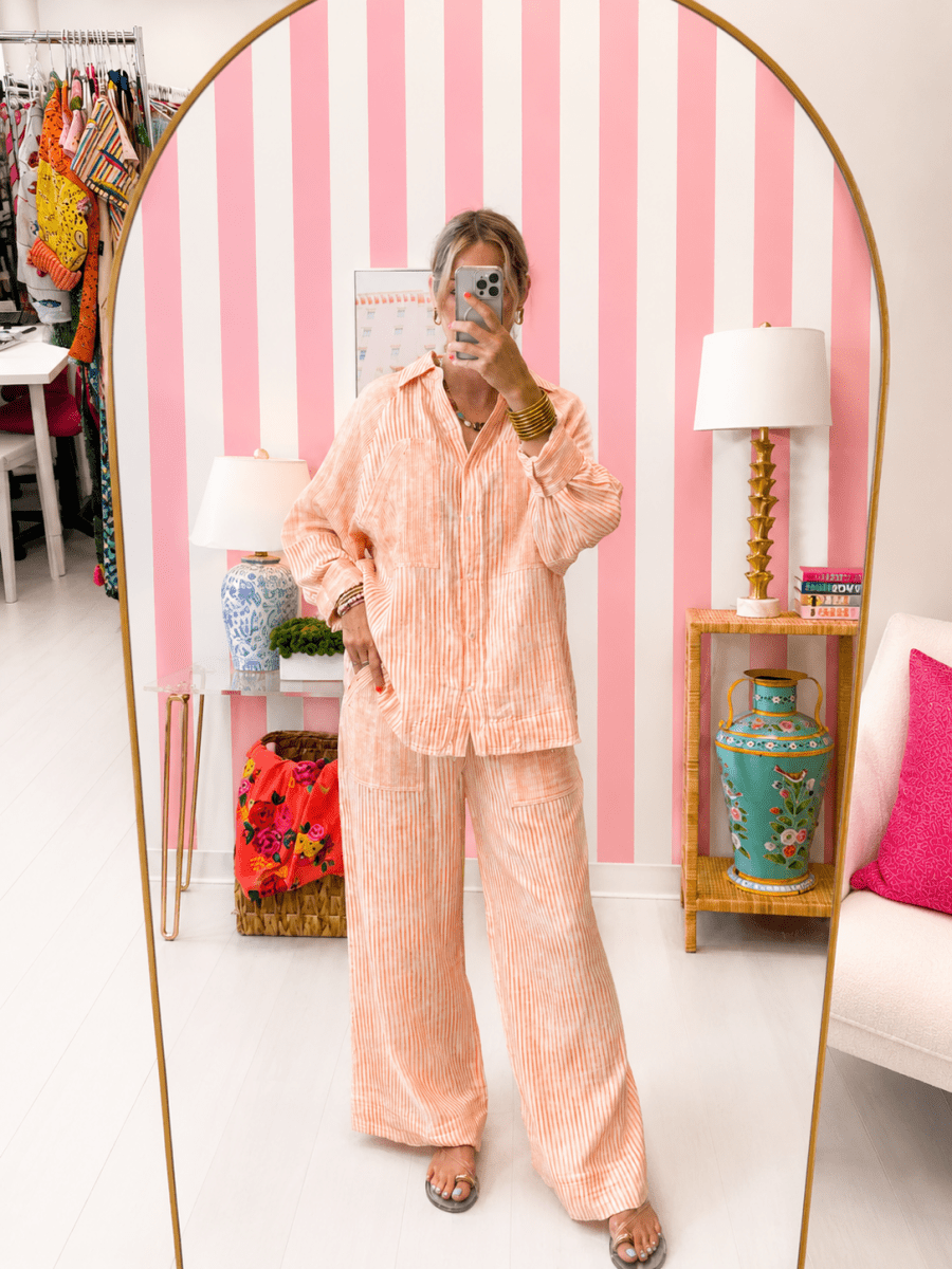 Person wearing a peach striped pajama set in a room with pink and white striped walls.