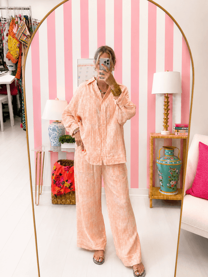 Person wearing a peach striped pajama set in a room with pink and white striped walls.