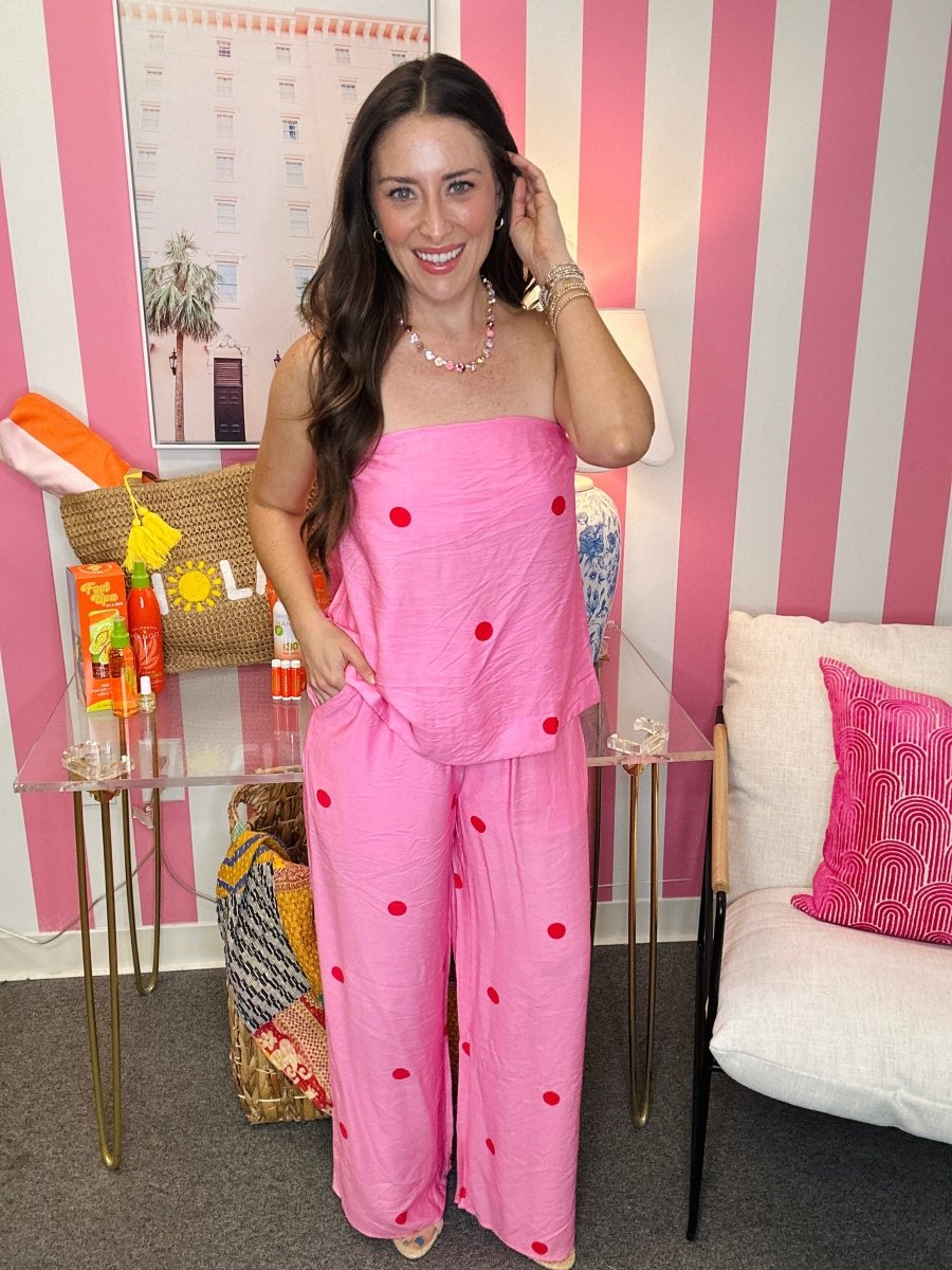 Woman in a pink outfit standing in a room with striped walls and decorative items.