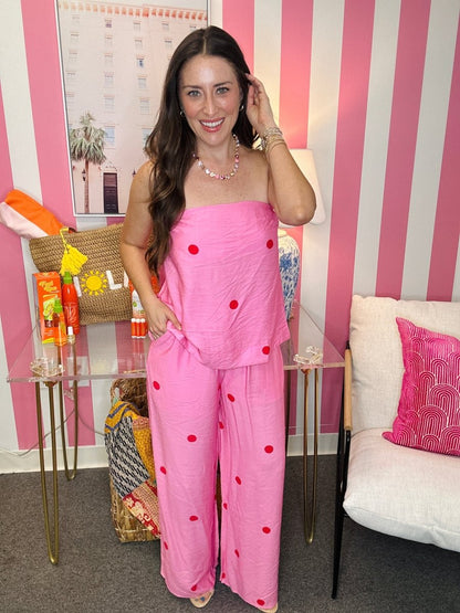 Woman in a pink outfit standing in a room with striped walls and decorative items.