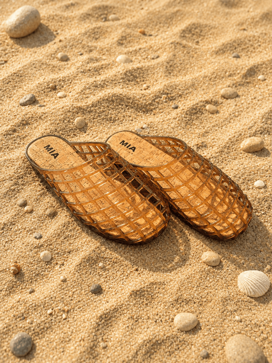 Brown sandals with 'MIA' branding on a sandy surface