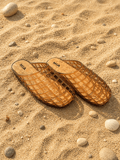 Brown sandals with 'MIA' branding on a sandy surface
