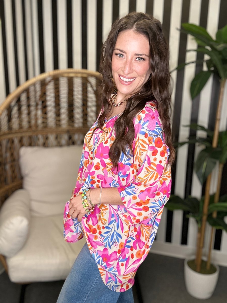 Woman wearing a colorful floral blouse in a living room setting