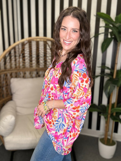 Woman wearing a colorful floral blouse in a living room setting