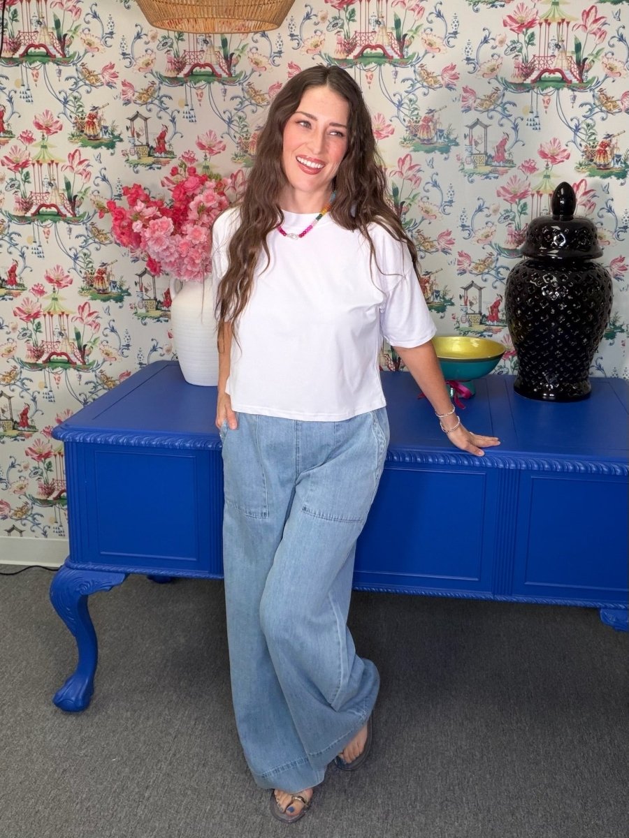 Woman standing in front of a blue cabinet with floral wallpaper in the background