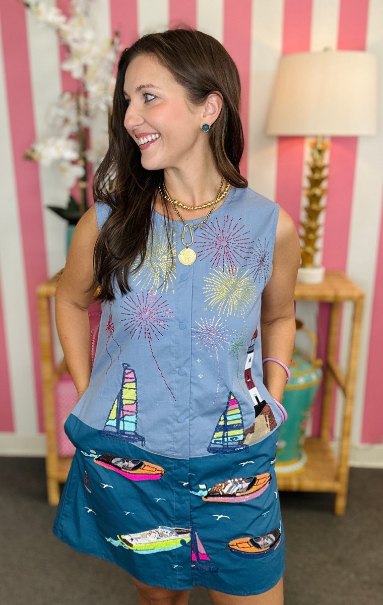 Woman wearing a blue outfit with sailboat designs in a room with striped wallpaper.