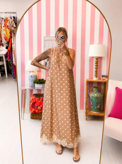 Woman in a polka dot dress standing in a room with striped walls and decorative items.