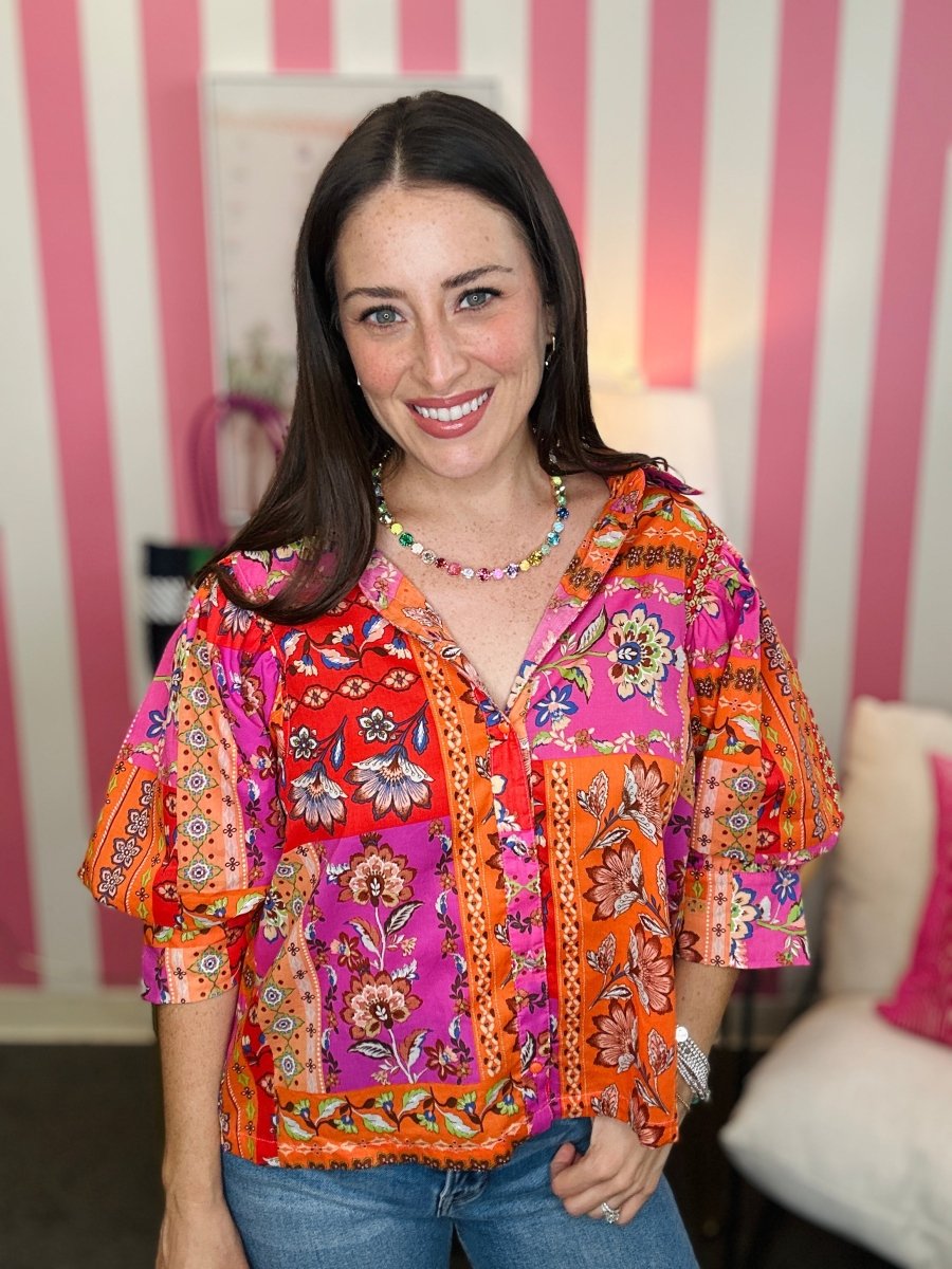 Woman wearing a colorful patterned blouse with a striped wall in the background
