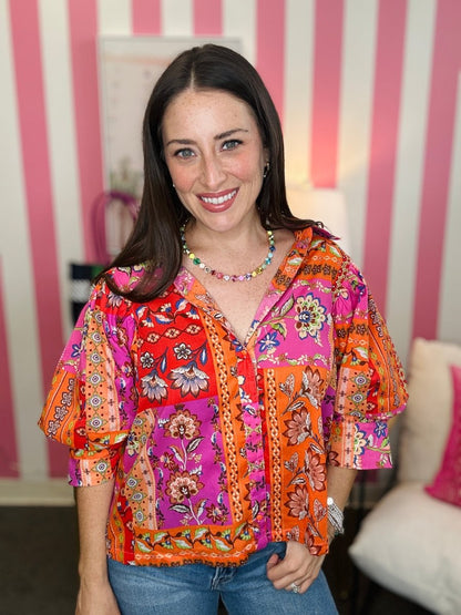 Woman wearing a colorful patterned blouse with a striped wall in the background