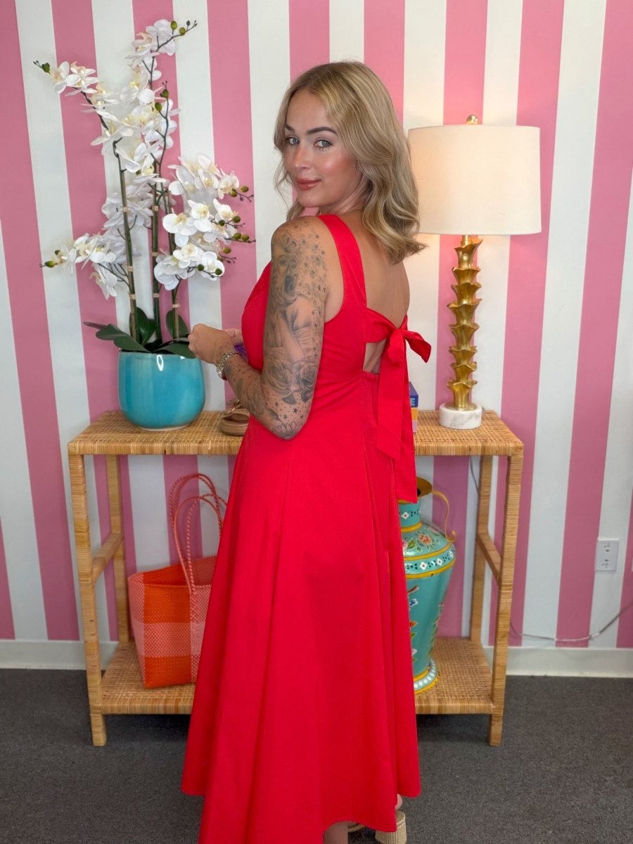Woman in a red dress standing in a room with striped walls and decorative items.