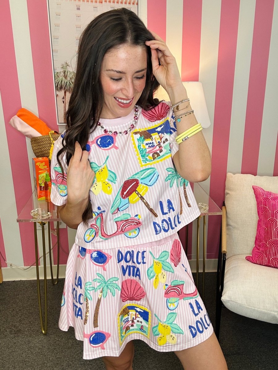 Woman wearing a colorful dress with text and graphics in a room with striped walls.