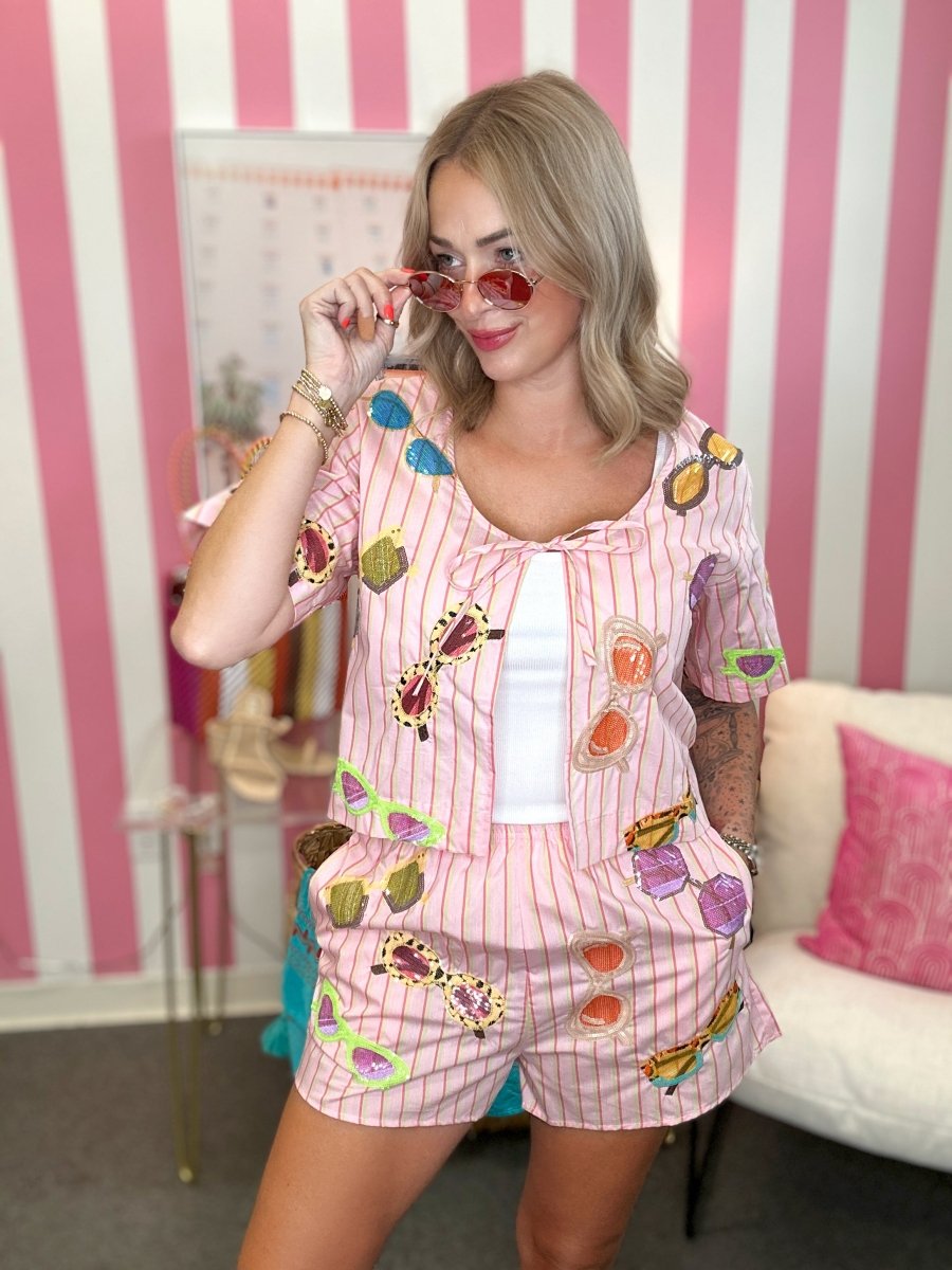 Woman wearing a colorful pajama set with a striped pink and white wall in the background