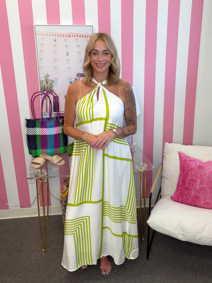 Woman in a white and green dress standing in front of a pink and white striped wall.