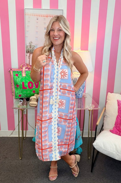 Woman posing in a colorful dress with a striped pink and white wall in the background