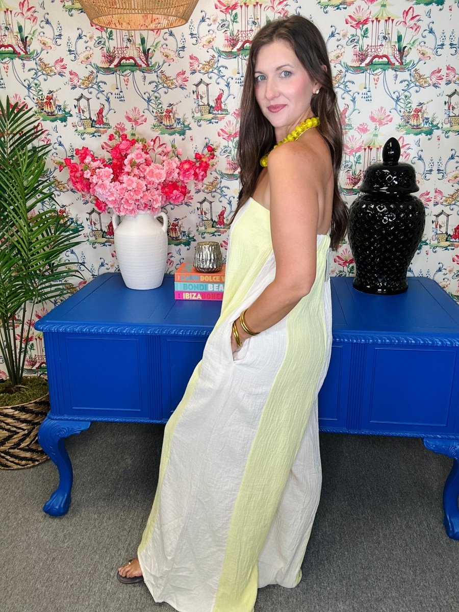 Woman in a white and yellow dress standing in front of a colorful wall with floral patterns.