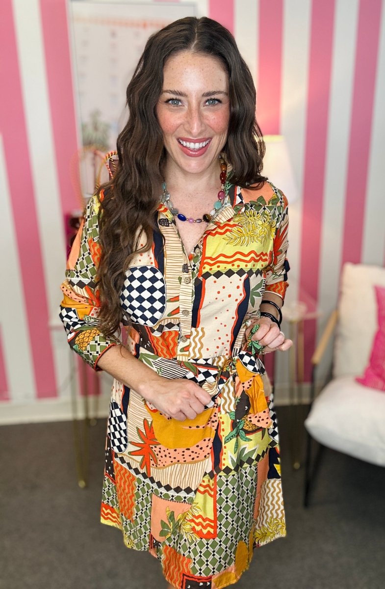 Woman wearing a colorful patterned dress in a room with striped walls.