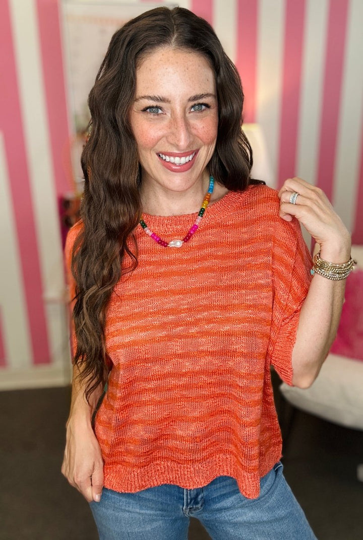 Woman wearing an orange striped shirt with a pink and white striped background