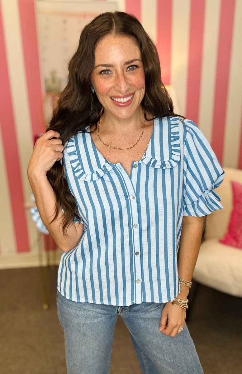 Woman wearing a blue and white striped shirt with a blurred indoor background