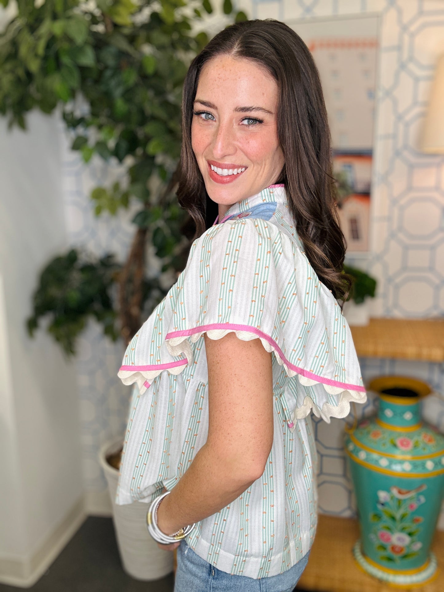 Woman wearing a light-colored blouse with ruffled sleeves in an indoor setting.
