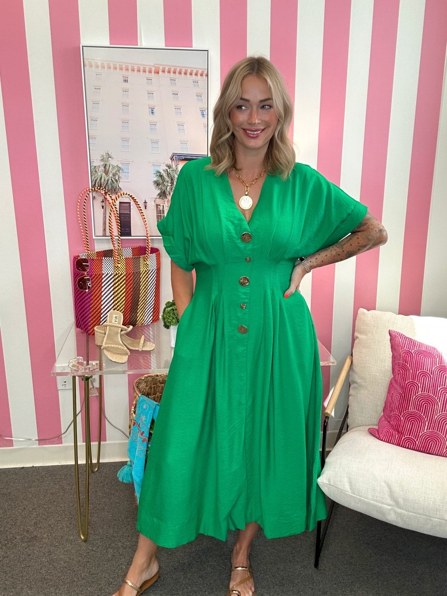 Woman in a green dress standing in a room with pink and white striped walls.