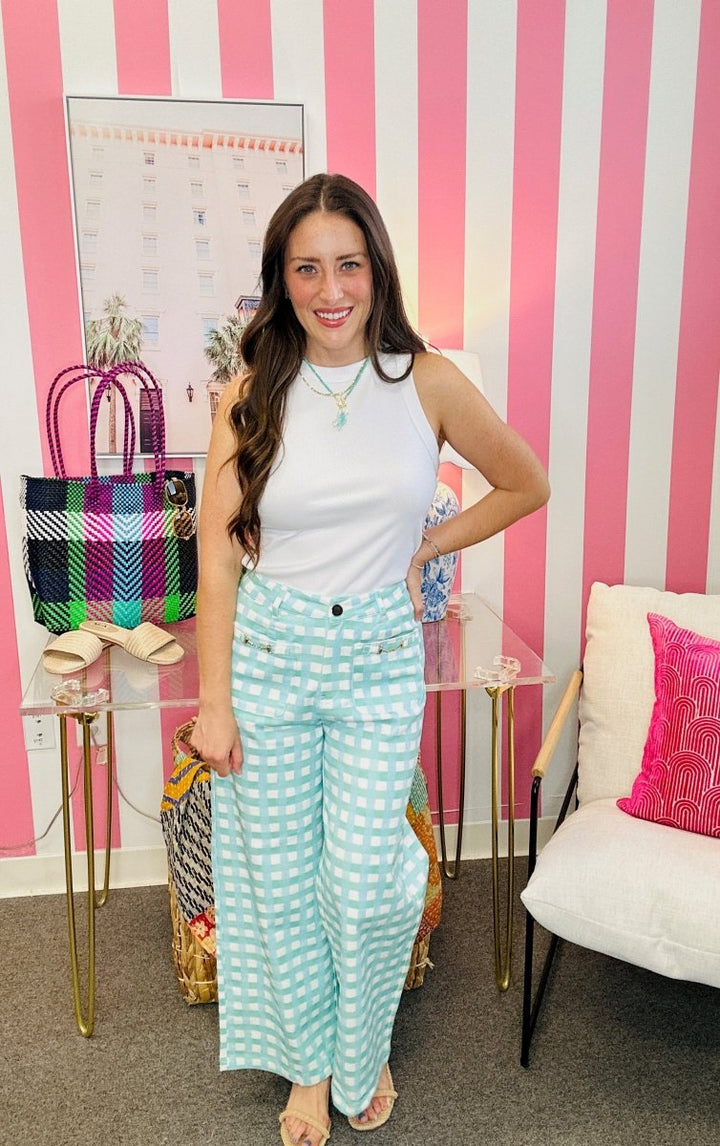 Woman posing in a room with pink and white striped walls, colorful bags, and a chair.