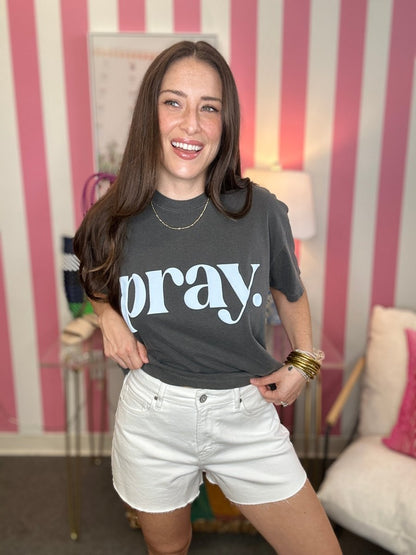 Woman wearing a black t-shirt with 'pray.' text in a casual setting.