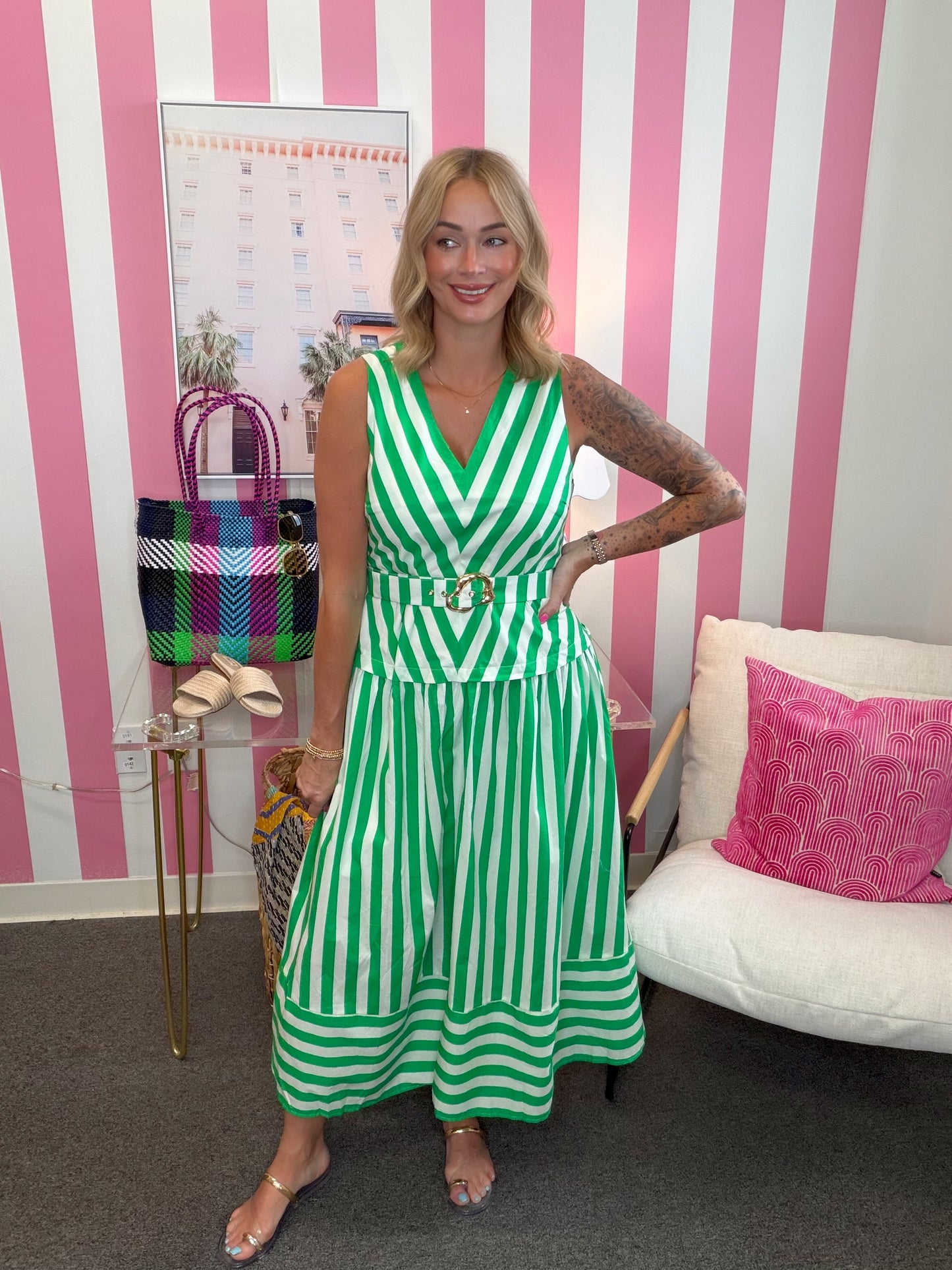 Woman in a green and white striped dress standing in a room with pink and white striped walls.