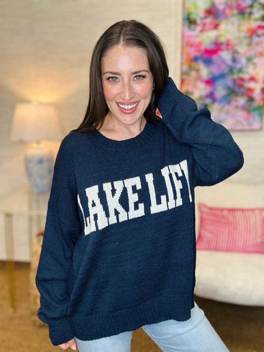 Woman wearing a navy sweater with 'LAKE LIFT' text in a living room setting