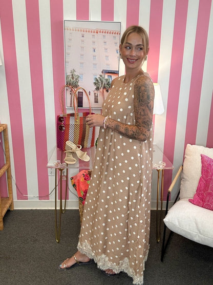Woman in a polka dot dress standing in a room with pink and white striped walls.