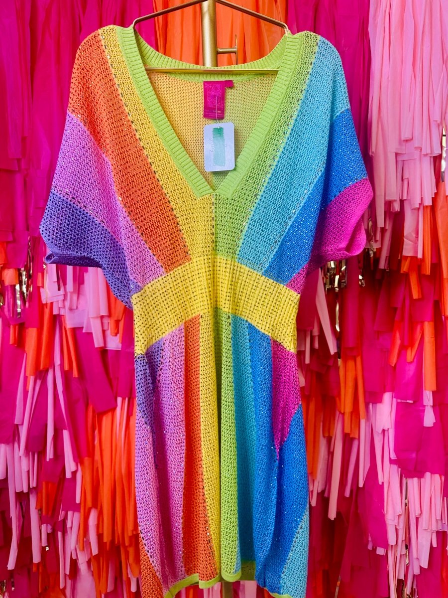 Colorful knitted cardigan on a hanger against a vibrant pink and orange background