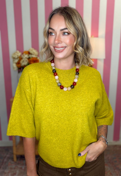 woman standing in green yellow short sleeve sweater.