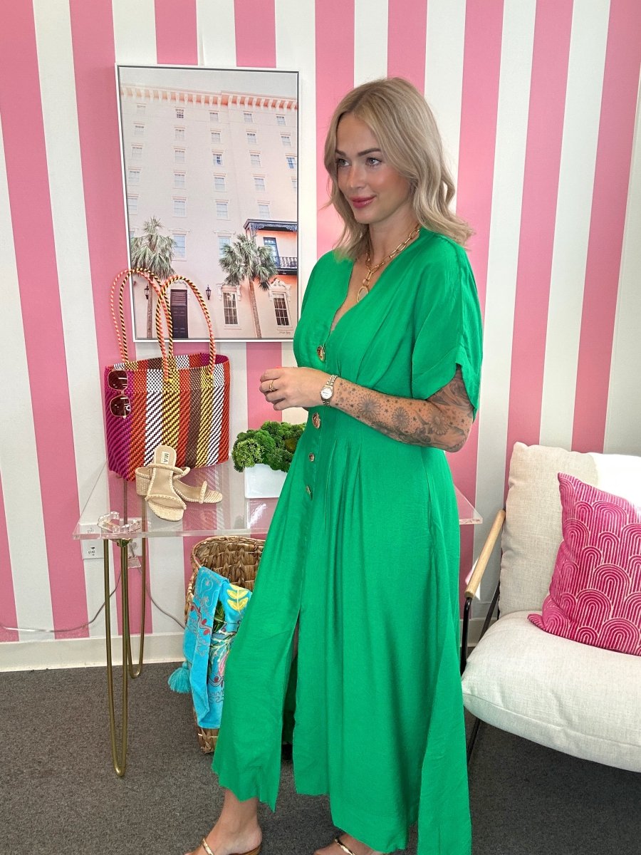 Woman in a green dress standing in a room with pink and white striped walls.