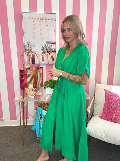 Woman in a green dress standing in a room with pink and white striped walls.