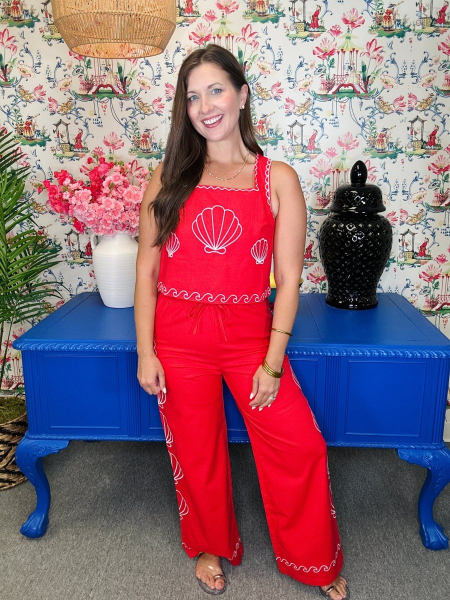 Woman in a red outfit standing in front of a colorful wall with decorative elements.