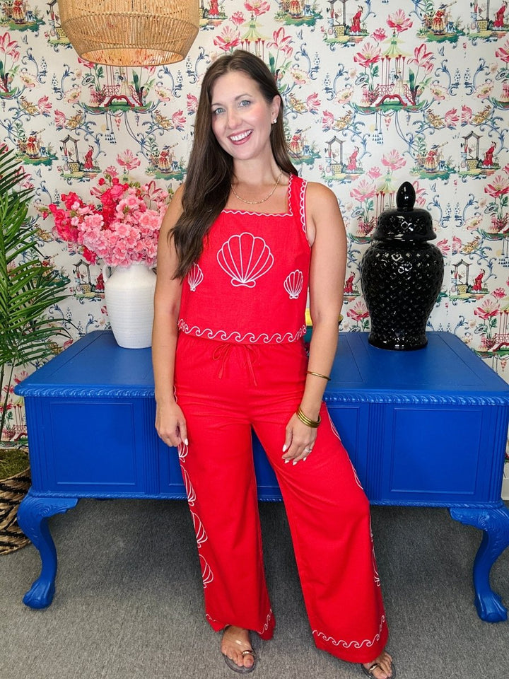 Woman in a red outfit standing in front of a colorful wall with decorative elements.