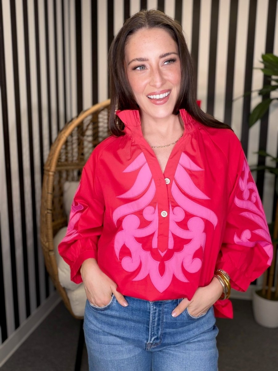 Woman wearing a red jacket with pink patterns in an indoor setting