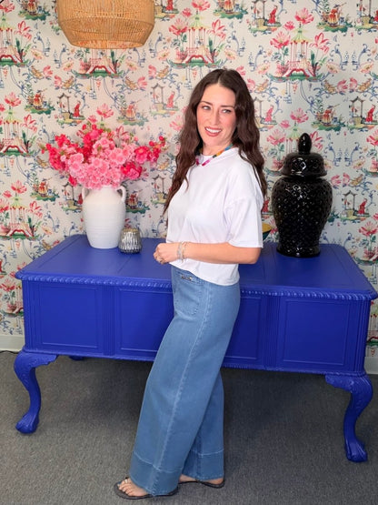 Woman standing next to a blue table with floral wallpaper in the background