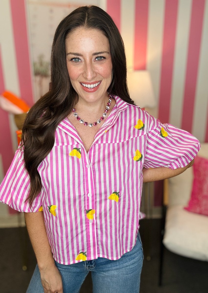 Woman wearing a pink and white striped shirt with yellow accents in a room with striped walls.